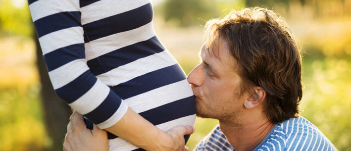 муж целует беременную жену